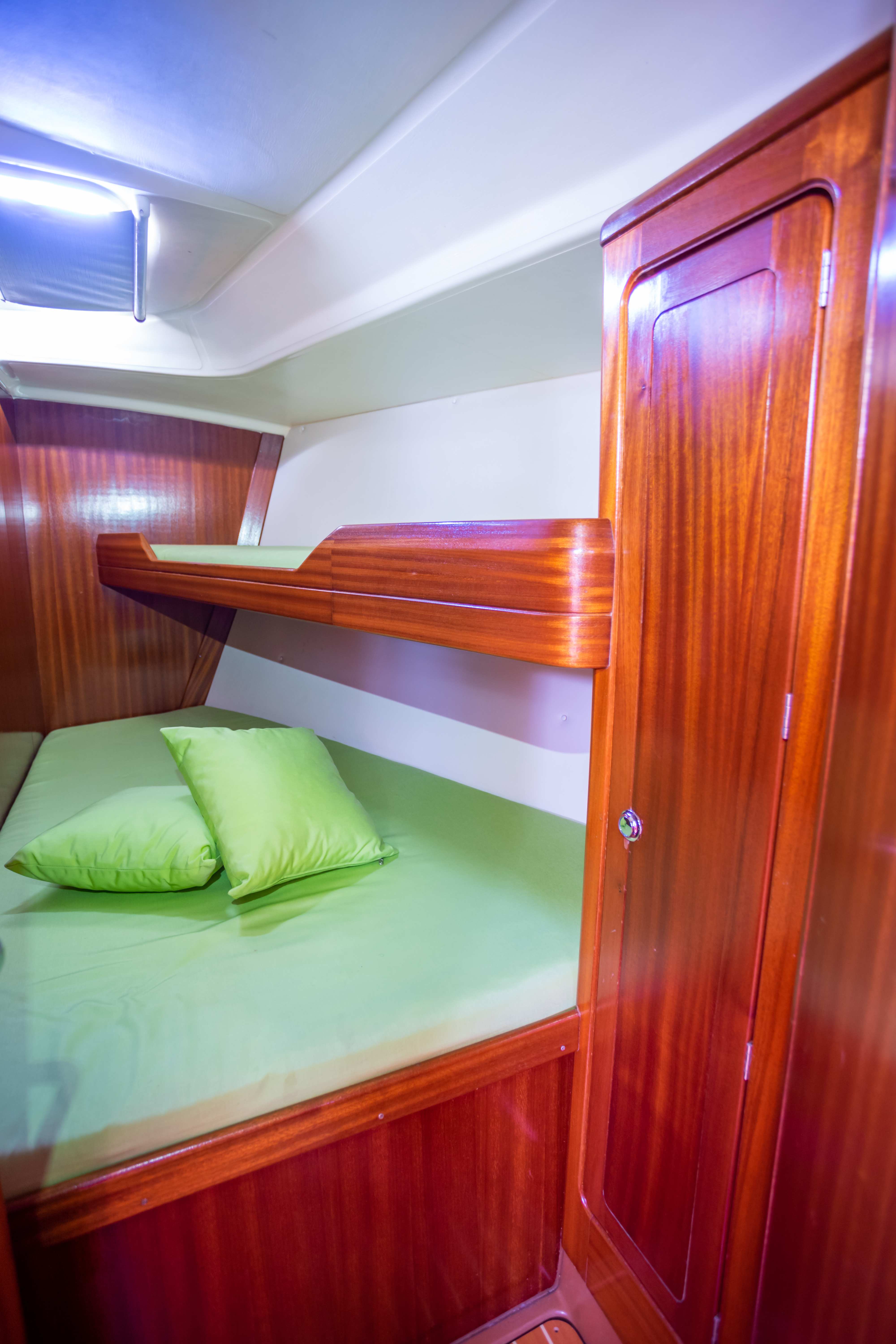 Cabin with green bedding and wooden cabinetry