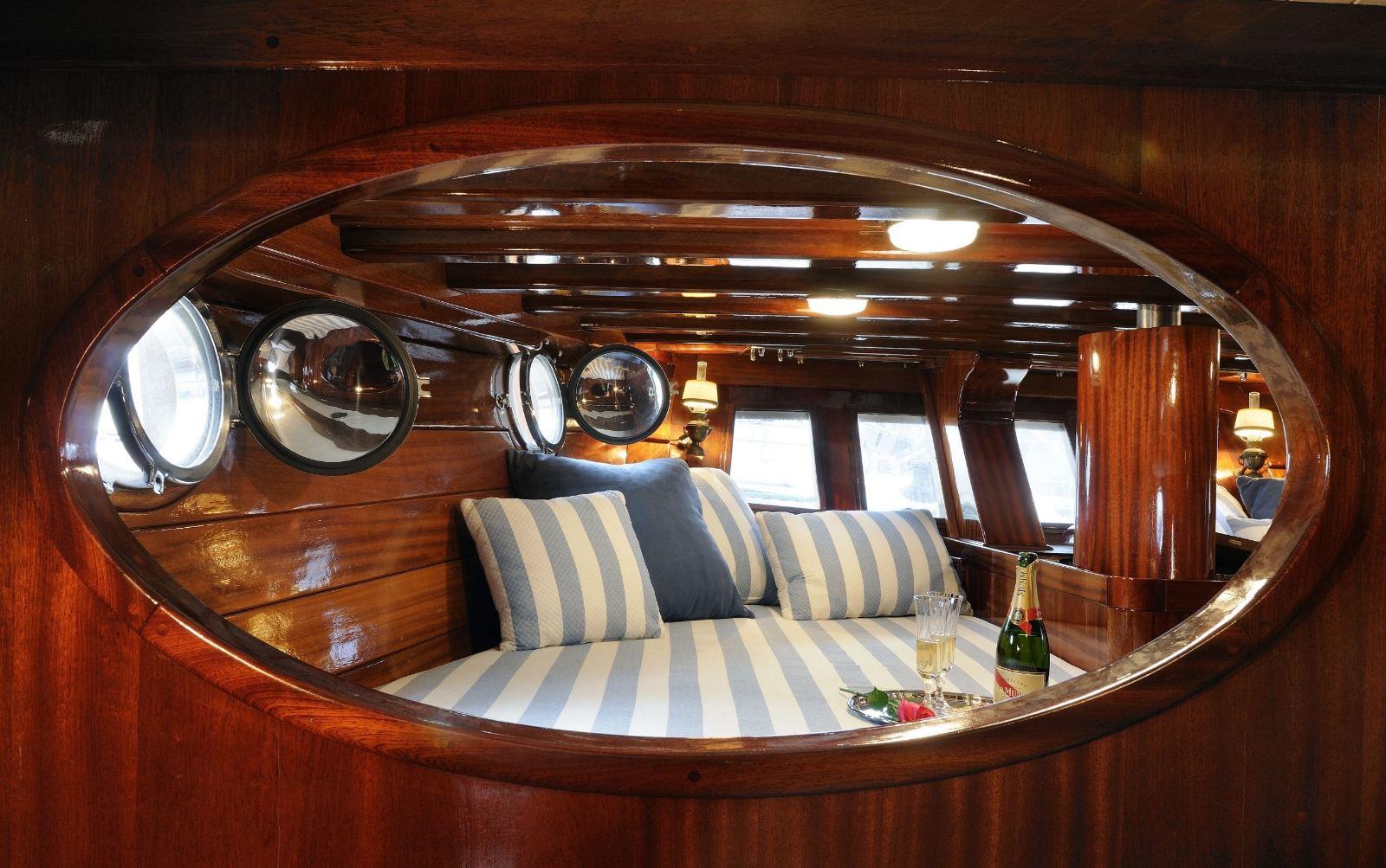 Interior view through an oval wooden doorway showing the cabin with blue and white striped cushions